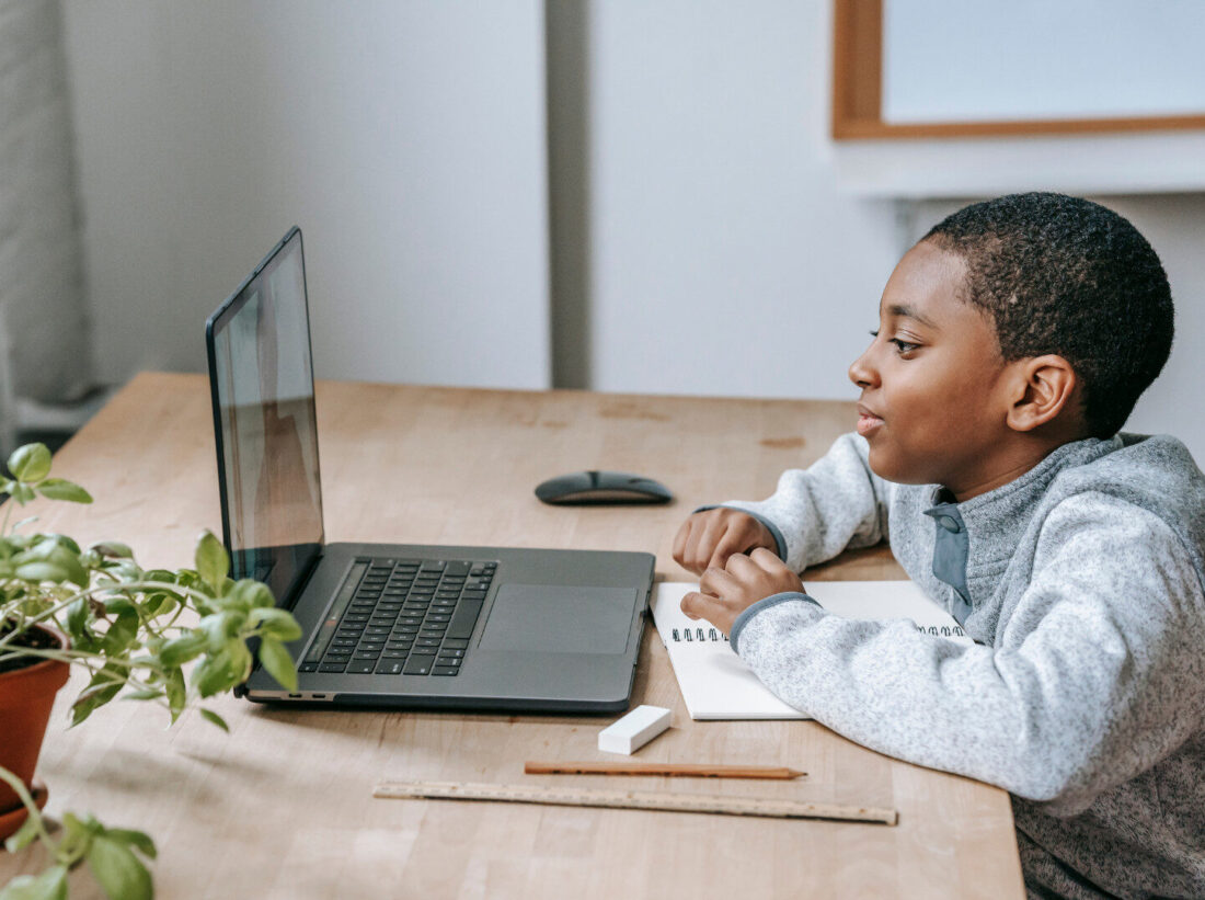 A child sat at a desk looking at a laptop A child sat at a desk looking at a laptop