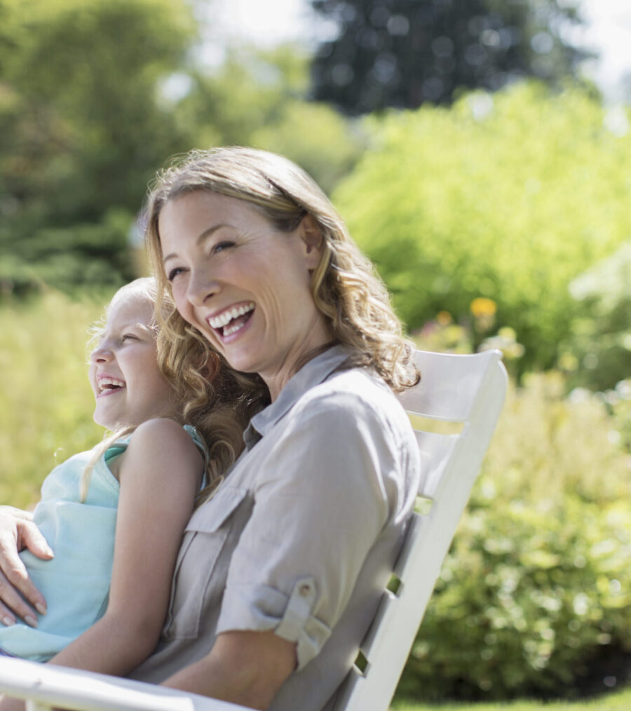 A woman sat on an outdoor chair with her daughter on her lap, smiling