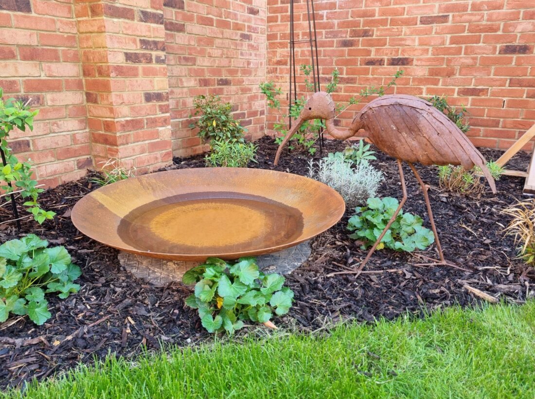 A natural water feature in a garden with a heron