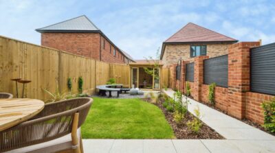 A landscaped show home garden with extended patio, turf, seating area and summer house