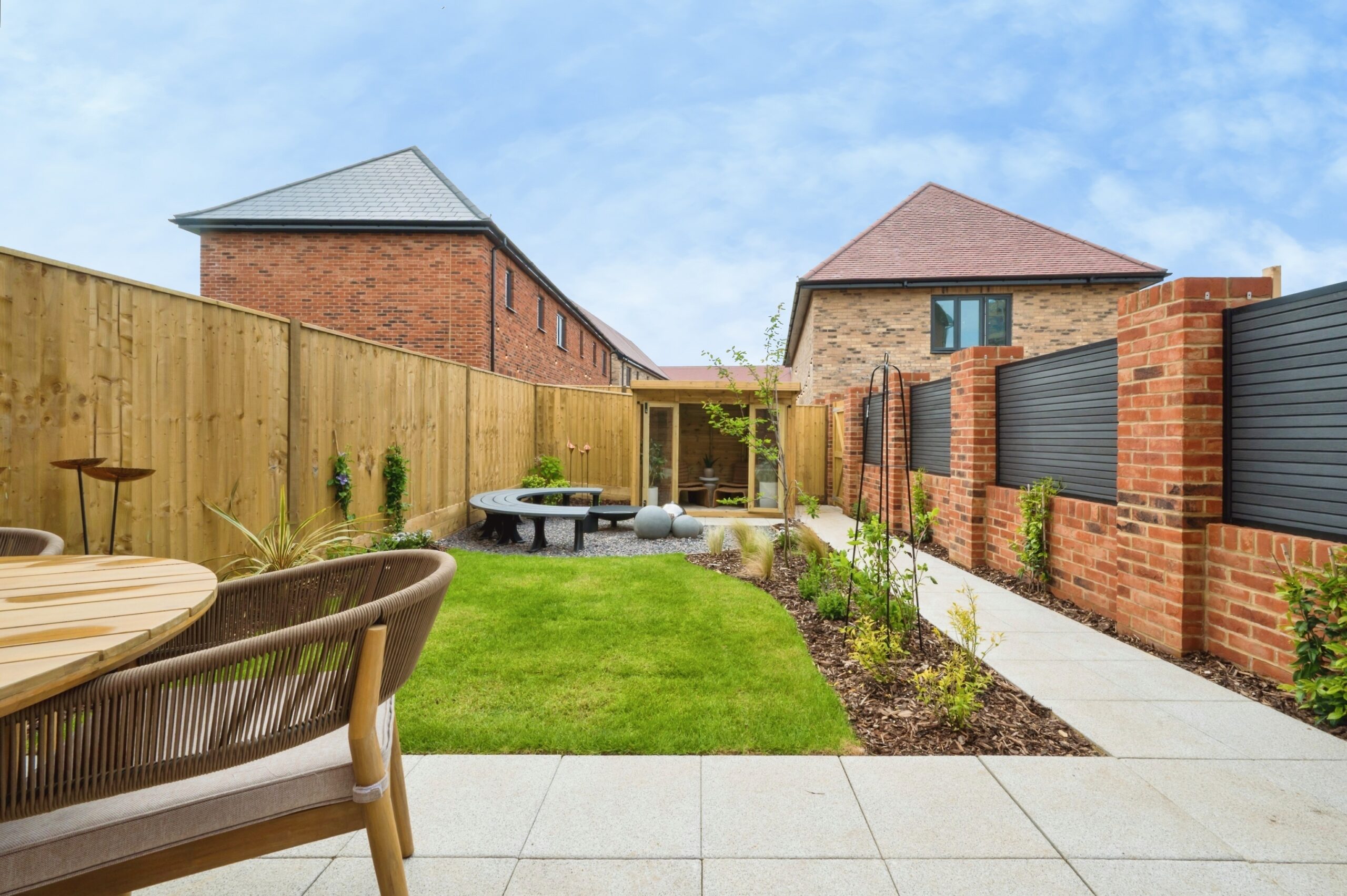 A landscaped show home garden with extended patio, turf, seating area and summer house