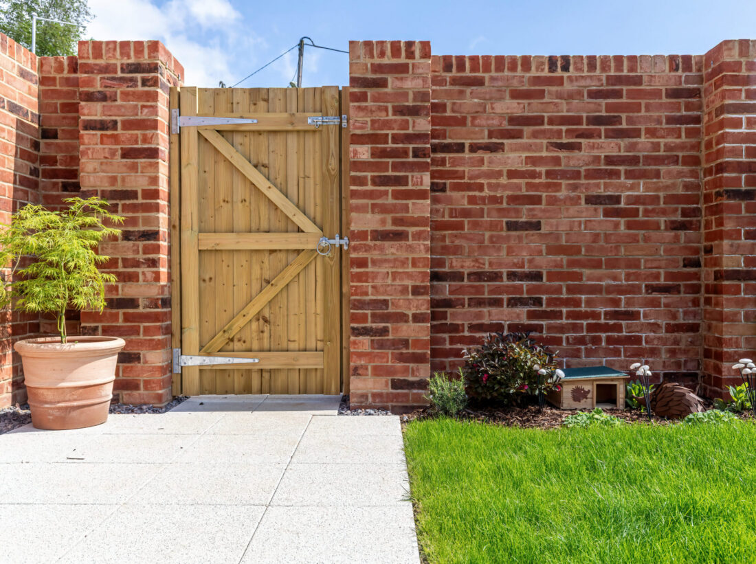 A garden with showing a brick wall, fence, lawn and patio