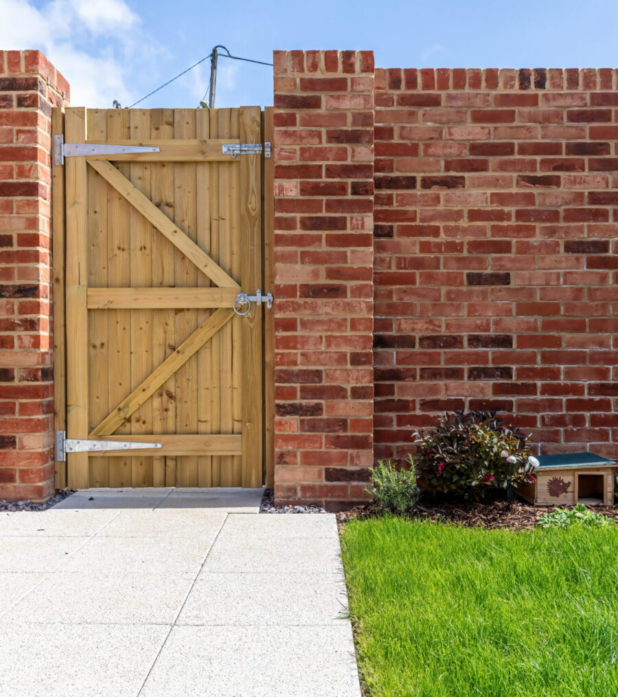 A garden with showing a brick wall, fence, lawn and patio
