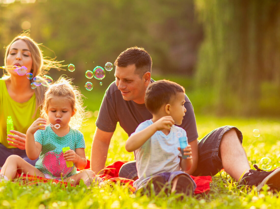 A family sat down in a park blowing bubbles